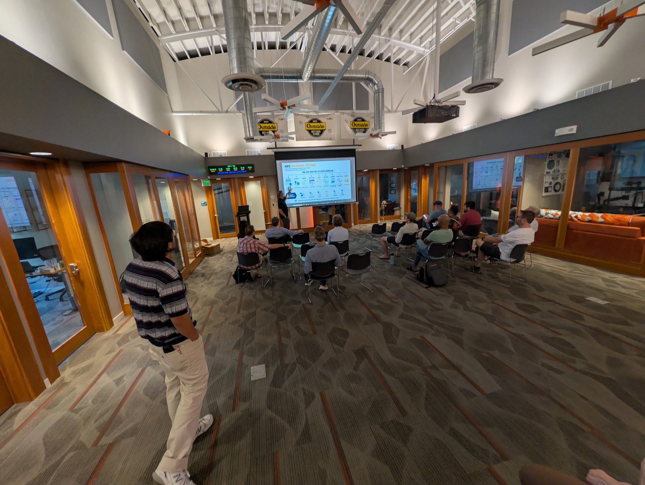 Wide view of the Rule 4 great room with attendees seated for a slide on AWS database options